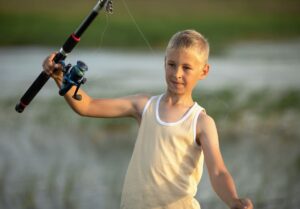 garçon est pêche à le coucher du soleil sur le Lac